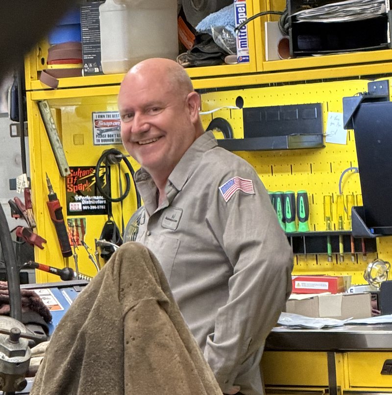Andy smiling in front of the tool wall at AVEC