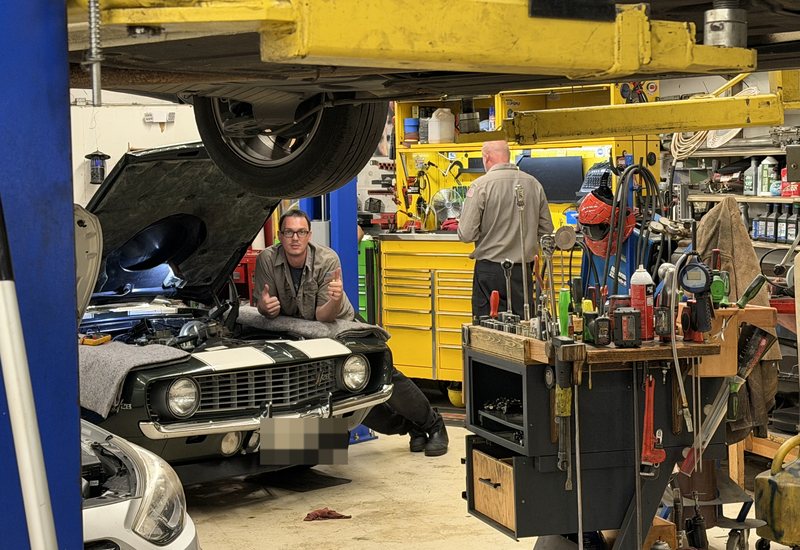 A technician gives two thumbs up beside a classic 1969 Camaro Z/28 in the AVEC shop