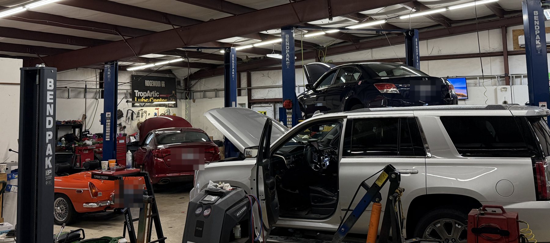 The AVEC shop floor: cars on BendPak lifts, a classic MG roadster, and work underway in several bays